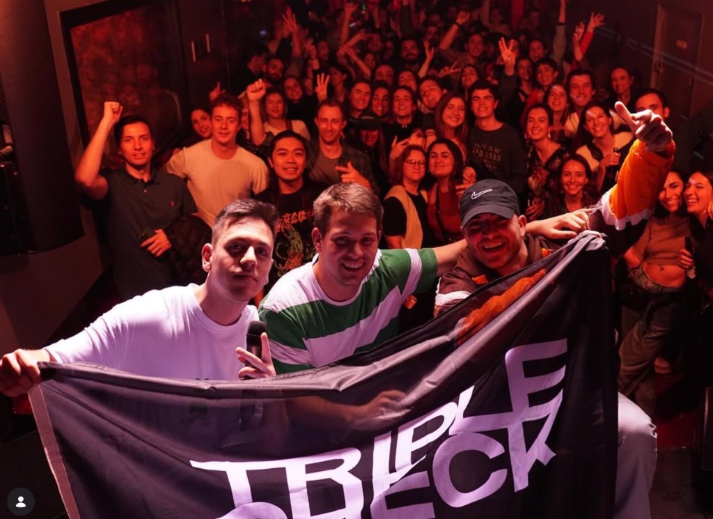 Triple Check — indoor venue, band with TRIPLE CHECK flag and audience
